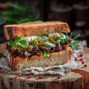 Sandwich with pulled pork and pickles with sauce.