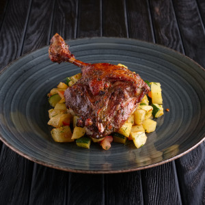 Roasted quail leg with fried potato cubes, zuccini and tomato