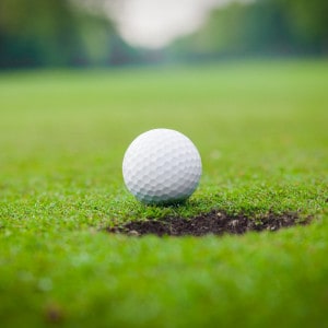 golf ball on lip of cup. Golf ball on green grass in golf course